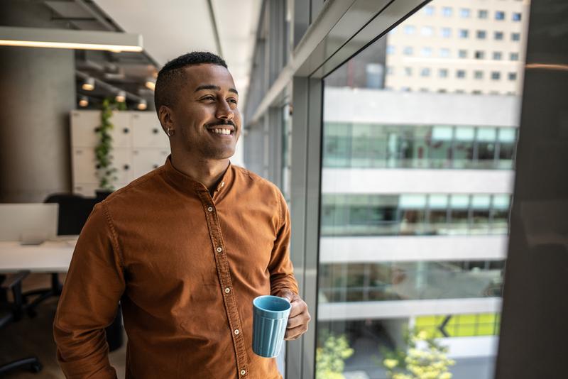 man in office looking out window.