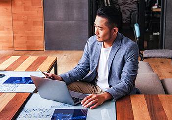 Image: man sitting at desk with laptop and phone.
