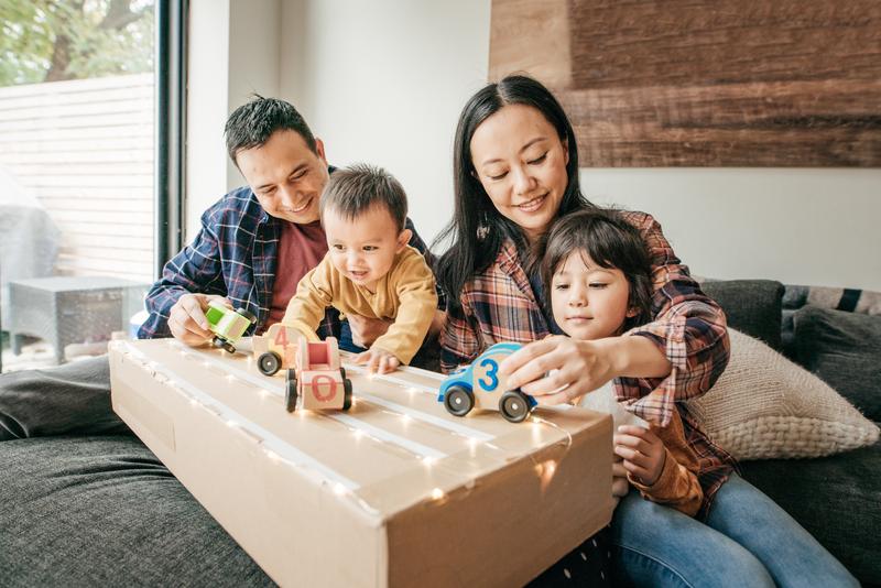 parents and children playing with wooden toy cars.