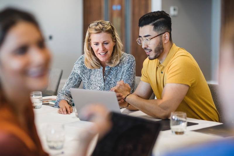 Man and a woman sitting at a conference room table in a meeting