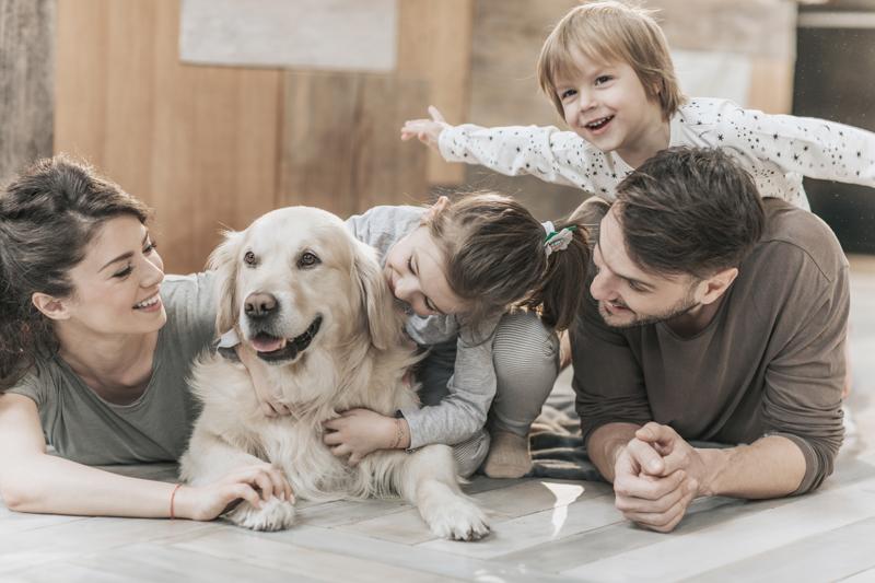 happy family relaxing on the floor with their dog at home