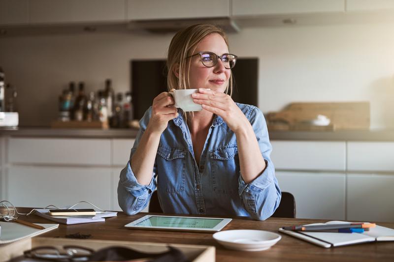 Image: woman sitting holding coffee cup.