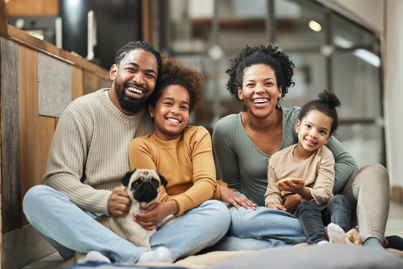 family sitting on floor smiling for camera.