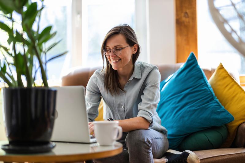 woman sitting on couch working on laptop.
