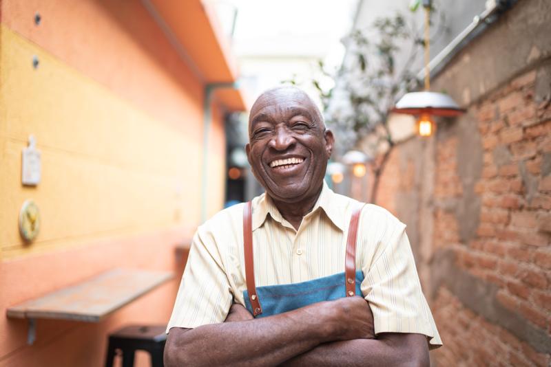 portrait of smiling elderly waiter looking at camera.
