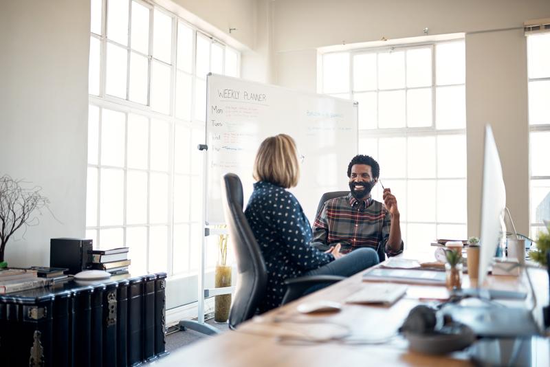 two mature businesspeople sitting in the office together and having a discussion.