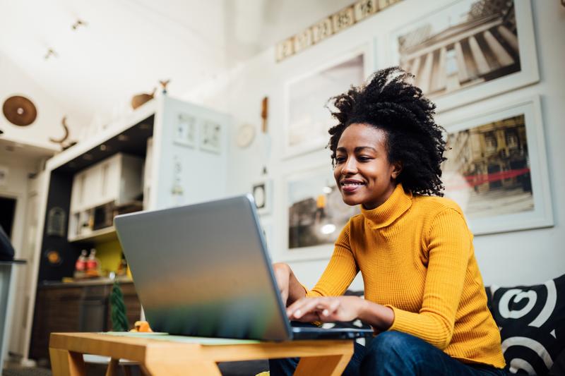 woman sitting on couch working on laptop.