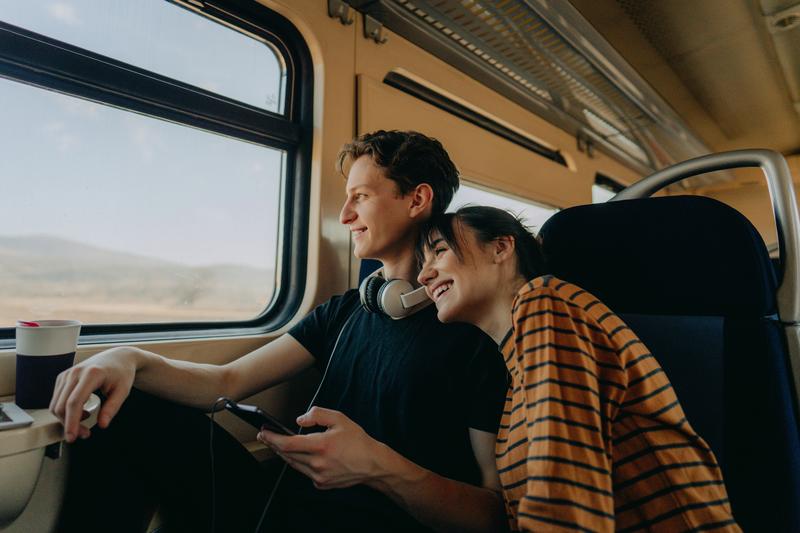 smiling young couple travelling together by train