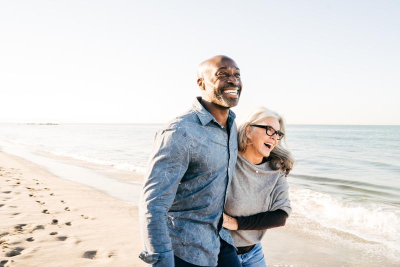 couple embrace walking on beach shore.
