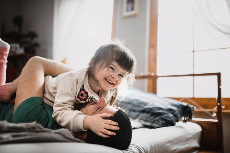 father and daughter playing in bed.