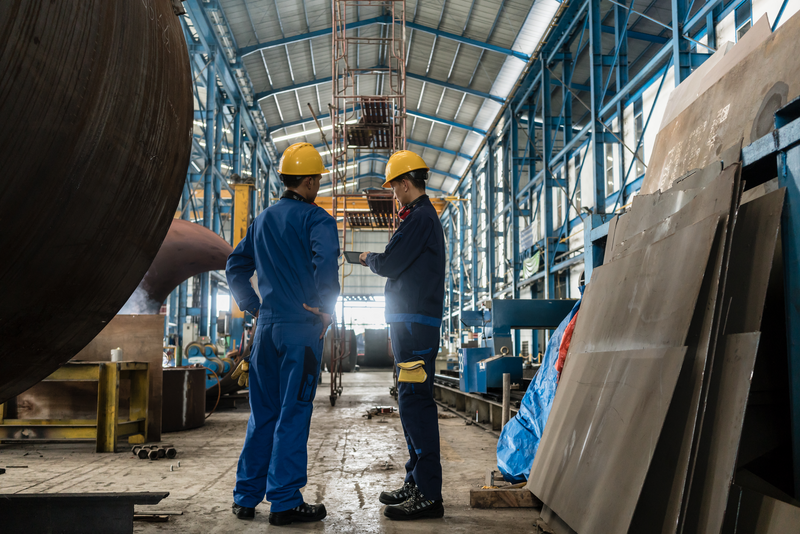 two men in hard hats having conversation in industrial setting