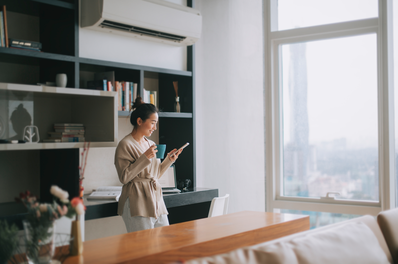 woman standing holding cup looking at phone