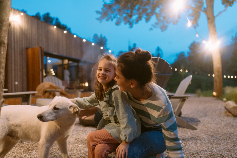 woman and young girl sitting outside and petting a dog