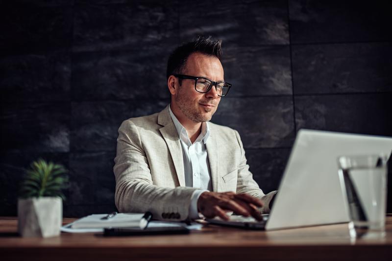 man with glasses in business attire working on laptop