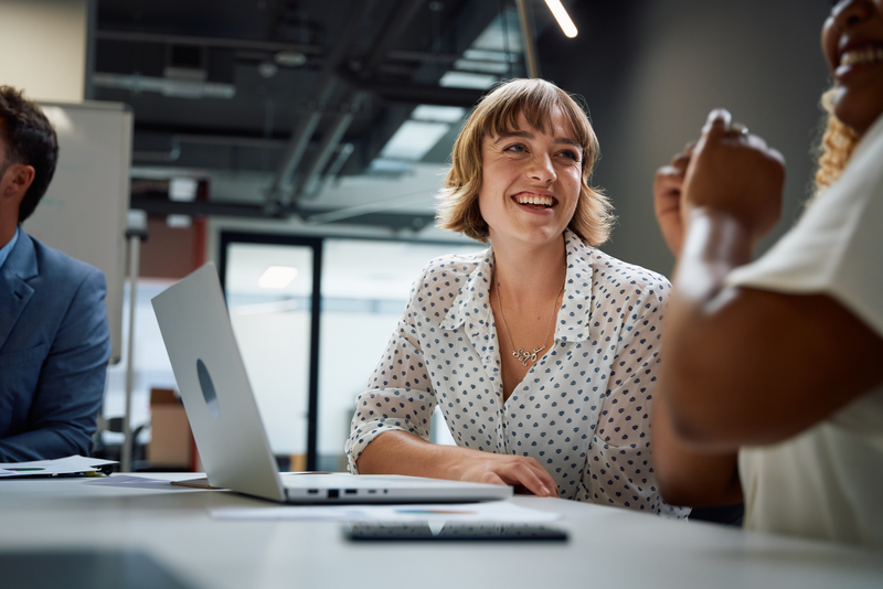 businesspeople in businesswear smiling during discussion at meeting in office