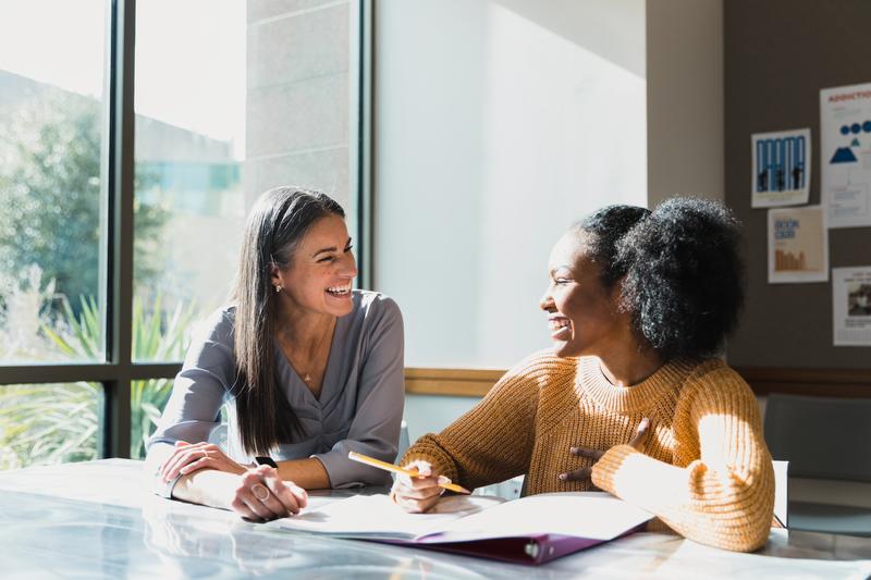 Two women meeting in a bright, sunny room.