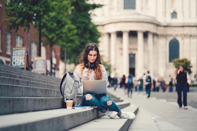 woman dressed casual sitting on steps with laptop.