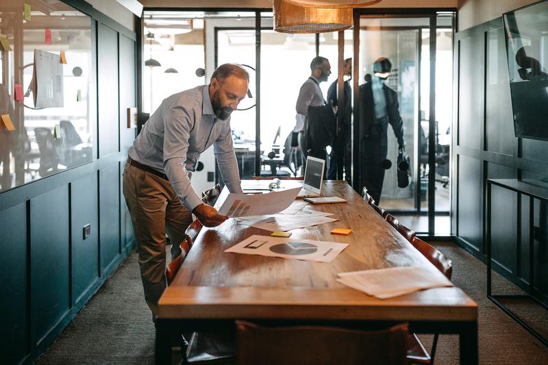 Man leaning over a desk reviewing documents.